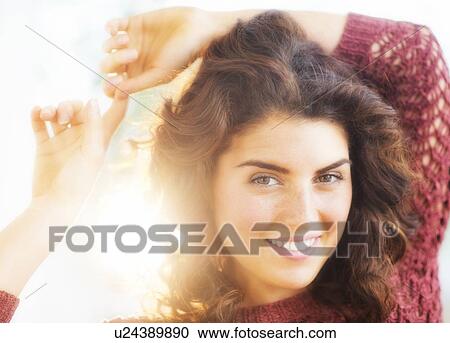 Stock Image - Portrait of smiling woman in backlit. Fotosearch
