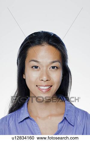 Stock Image - Portrait of smiling young woman, studio shot. Fotosearch