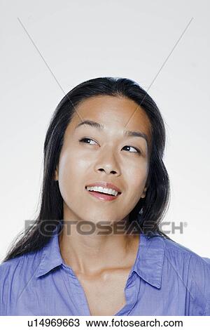 Stock Image - Portrait of smiling young woman, studio shot. Fotosearch