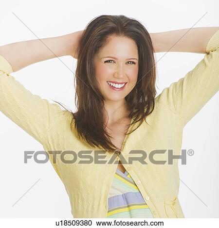 Stock Image - Portrait of smiling young woman, studio shot. Fotosearch