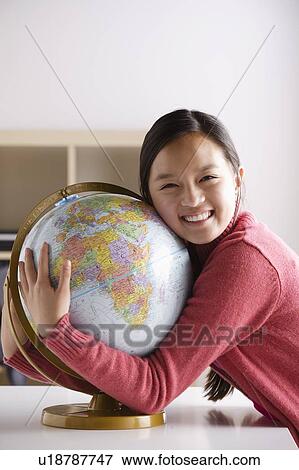 Stock Photo - Portrait of teenage girl (14-15) with globe. Fotosearch