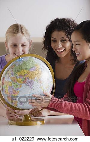 Stock Photo - Portrait of teenage girls (14-15, 16-17) with globe. Fotosearch