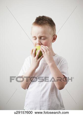 Stock Image - Portrait of toddler boy (2-3) devouring green apple. Fotosearch