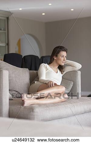 Stock Image - Portrait of woman sitting on couch. Fotosearch