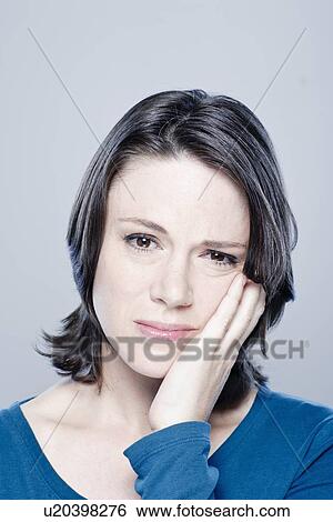 Stock Photograph - Portrait of worried mid adult woman, studio shot. Fotosearch