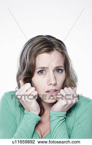 Stock Image - Portrait of worried young woman, studio shot. Fotosearch