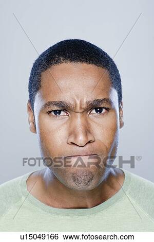 Stock Photograph - Portrait of young angry man, studio shot. Fotosearch