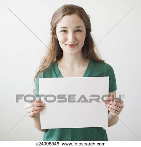 Stock Photography - Portrait of young attractive woman holding blank sheet of paper. Fotosearch