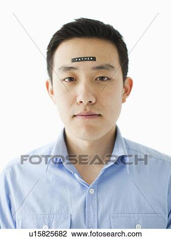 Stock Image - Portrait of young man with word 'father' on forehead, studio shot. Fotosearch