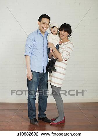Stock Image - Portrait of young parents with baby girl (12-17 months). Fotosearch