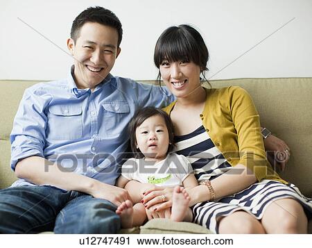 Stock Image - Portrait of young parents with baby girl (12-17 months). Fotosearch