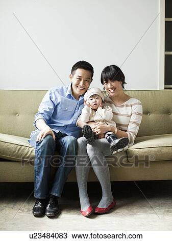 Stock Image - Portrait of young parents with baby girl (12-17 months). Fotosearch