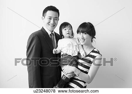 Stock Photo - Portrait of young parents with baby girl (12-17 months). Fotosearch