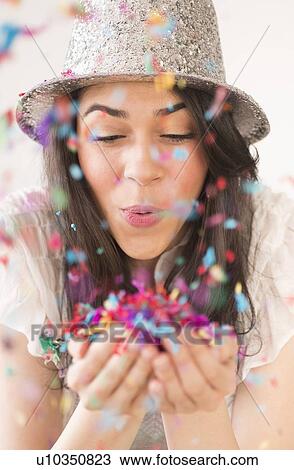 Portrait of young woman blowing confetti View Large Photo Image Stock Image - Portrait of young woman blowing confetti. Fotosearch