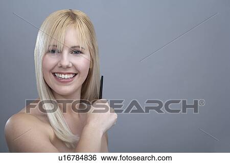 Portrait of young woman combing hair, studio shot View Large Photo Image Stock Photograph - Portrait of young woman combing hair, studio shot. Fotosearch