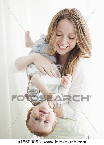 Portrait of young woman embracing baby boy (6-11 months) upside-down View Large Photo Image Stock Image - Portrait of young woman embracing baby boy (6-11 months) upside-down. Fotosearch