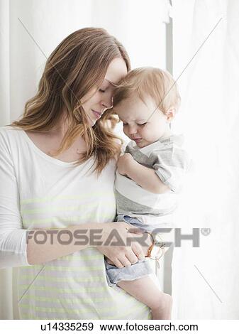 Stock Photo - Portrait of young woman embracing baby boy (6-11 months). Fotosearch