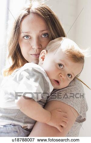 Stock Photo - Portrait of young woman embracing baby boy (6-11 months). Fotosearch