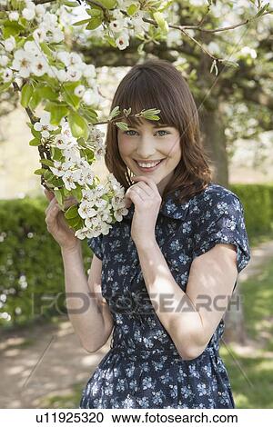 Stock Image - Portrait of young woman in blooming orchard. Fotosearch