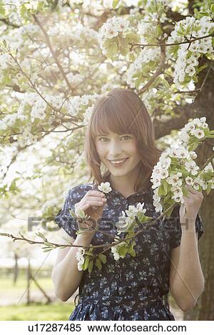 Stock Photography - Portrait of young woman in blooming orchard. Fotosearch