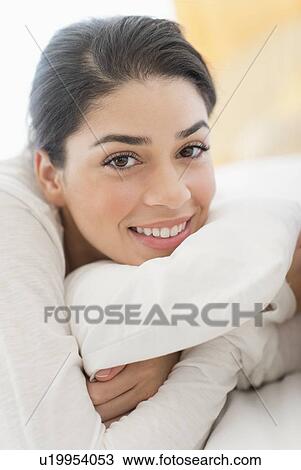 Stock Image - Portrait of young woman lying in bed. Fotosearch