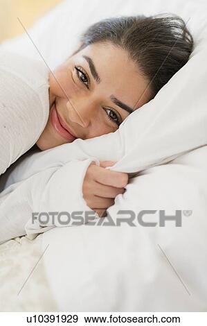 Stock Photo - Portrait of young woman lying in bed. Fotosearch
