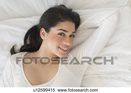 Portrait of young woman lying in bed View Large Photo Image Stock Photography - Portrait of young woman lying in bed. Fotosearch
