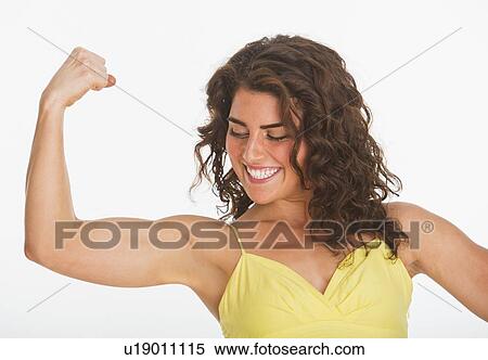 Portrait of young woman showing her biceps, studio shot View Large Photo Image Stock Photography - Portrait of young woman showing her biceps, studio shot. Fotosearch