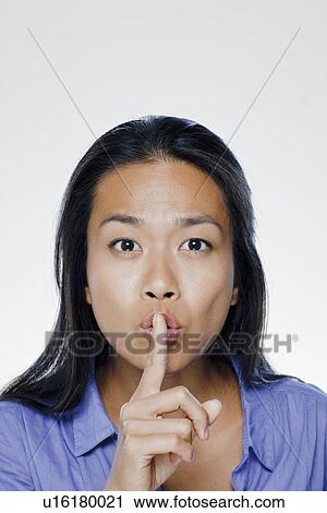 Portrait of young woman with finger on lips, studio shot View Large Photo Image Stock Image - Portrait of young woman with finger on lips, studio shot. Fotosearch