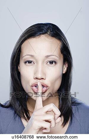Portrait of young woman with finger on her lips, studio shot View Large Photo Image Stock Photo - Portrait of young woman with finger on her lips, studio shot. Fotosearch