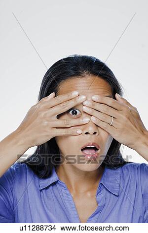 Portrait of young woman with hands covering eyes, studio shot View Large Photo Image Picture - Portrait of young woman with hands covering eyes, studio shot. Fotosearch