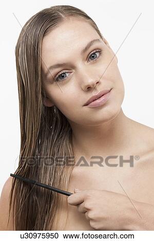 Stock Image - Portrait of young woman with wet hair and comb. Fotosearch