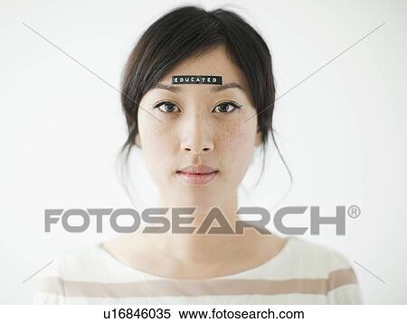 Stock Photography - Portrait of young woman with word 'educated' on forehead, studio shot. Fotosearch
