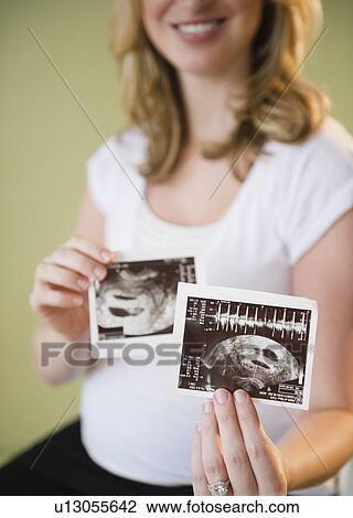 Stock Image - pregnant woman showing sonograms. Fotosearch