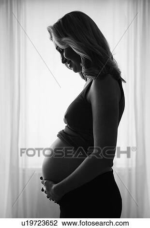 Pregnant woman standing by window View Large Photo Image Stock Image - Pregnant woman standing by window. Fotosearch