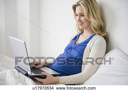 Pregnant woman using laptop in bed View Large Photo Image Picture - Pregnant woman using laptop in bed. Fotosearch