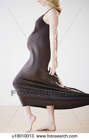 Stock Image - Pregnant woman wearing long black dress. Fotosearch