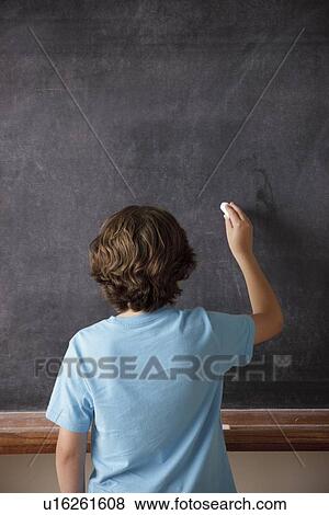 Rear view of schoolboy (10-11) writing on blackboard View Large Photo Image Stock Photo - Rear view of schoolboy (10-11) writing on blackboard. Fotosearch