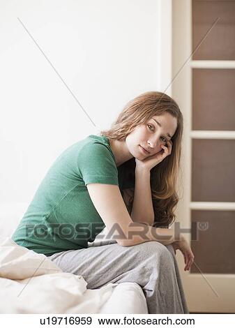 Stock Photo - Sad young woman sitting in bed. Fotosearch
