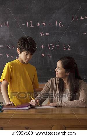 Stock Photo - Schoolboy (12-13) and teacher with blackboard in background. Fotosearch