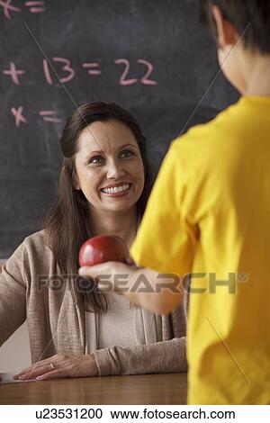 Schoolboy (12-13) giving apple to his teacher View Large Photo Image Stock Image - Schoolboy (12-13) giving apple to his teacher. Fotosearch