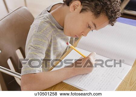 Schoolboy focused on writing in classroom View Large Photo Image Stock Photo - Schoolboy focused on writing in classroom. Fotosearch