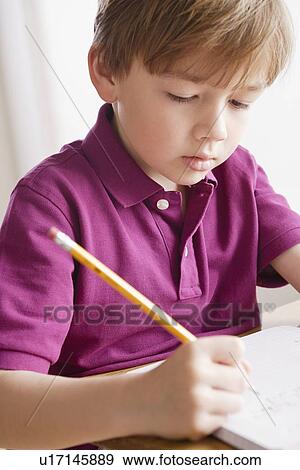 Schoolboy focused on writing in classroom View Large Photo Image Stock Photo - Schoolboy focused on writing in classroom. Fotosearch