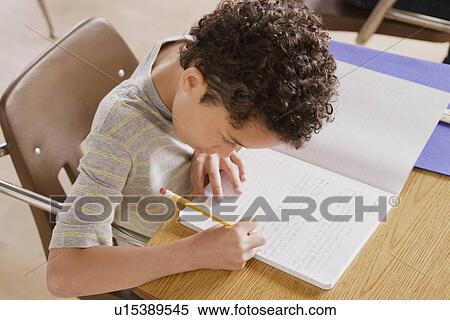 Stock Photography - Schoolboy focused on writing in classroom. Fotosearch