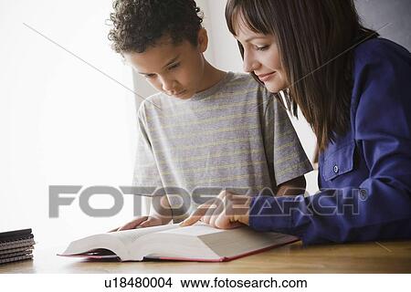 Schoolboy reading with teacher in classroom View Large Photo Image Picture - Schoolboy reading with teacher in classroom. Fotosearch