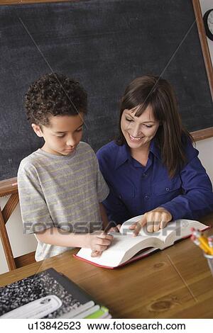 Schoolboy reading with teacher in classroom View Large Photo Image Stock Image - Schoolboy reading with teacher in classroom. Fotosearch