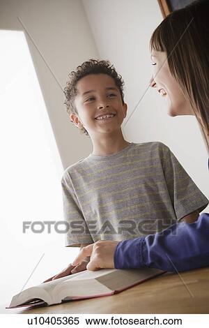 Stock Photography - Schoolboy reading with teacher in classroom. Fotosearch