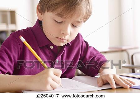 Stock Photo - Schoolboy writing in notebook. Fotosearch