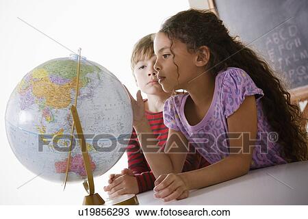 Stock Image - Schoolchildren (6-7) with globe. Fotosearch