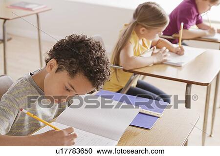 Schoolchildren focused on writing in classroom View Large Photo Image Stock Image - Schoolchildren focused on writing in classroom. Fotosearch